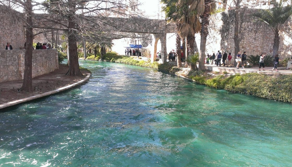 San Antonio River Walk with stroller family — calm canal waterway lined with trees and walkway paths in downtown San Antonio