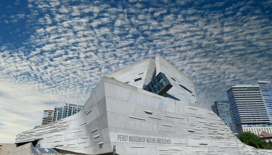 Perot Museum Dallas with kids — striking modernist exterior of the Perot Museum of Nature and Science against a dramatic Texas sky