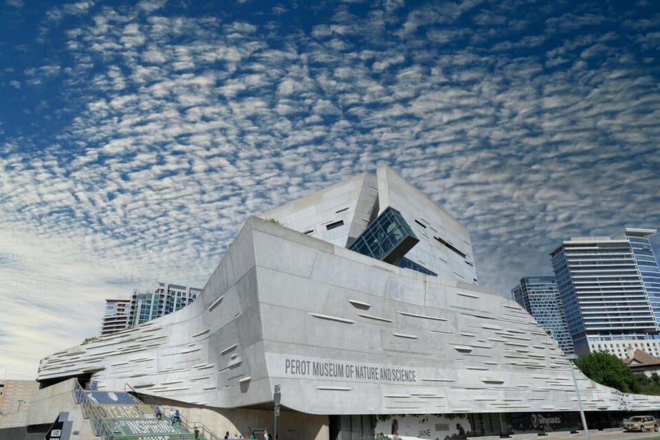 Perot Museum Dallas with kids — striking modernist exterior of the Perot Museum of Nature and Science against a dramatic Texas sky