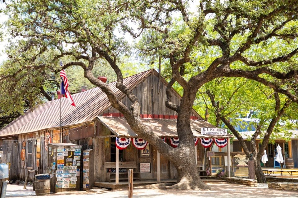Gruene Texas with kids — rustic Texas Hill Country wooden post office with American flag and live oak tree
