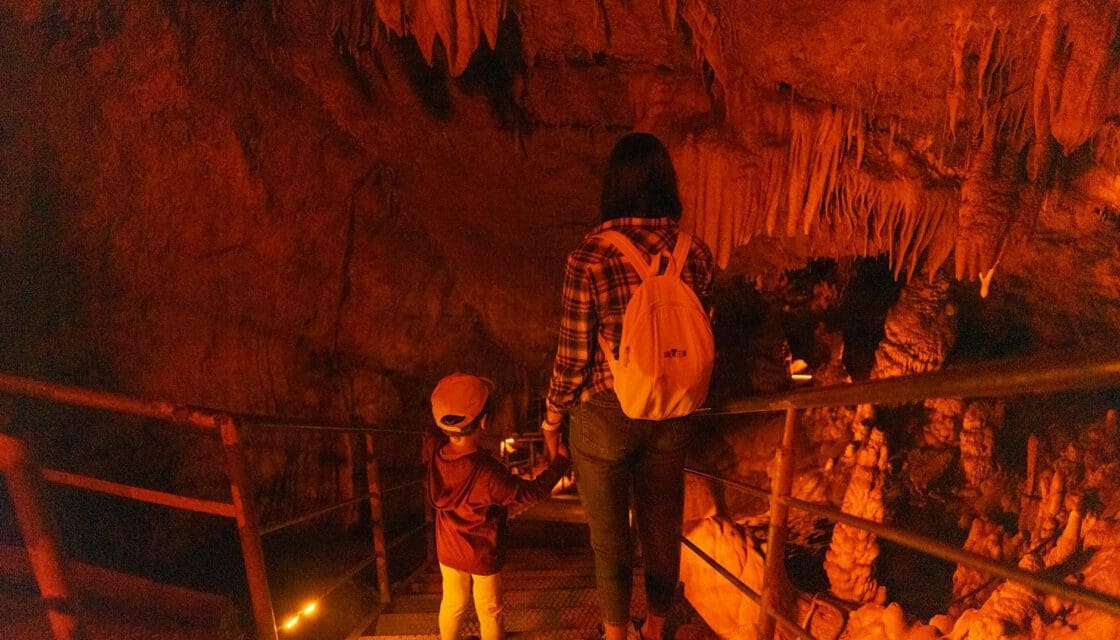 Natural Bridge Caverns with kids San Antonio — mother and child descending into a dimly lit cave surrounded by stalactites