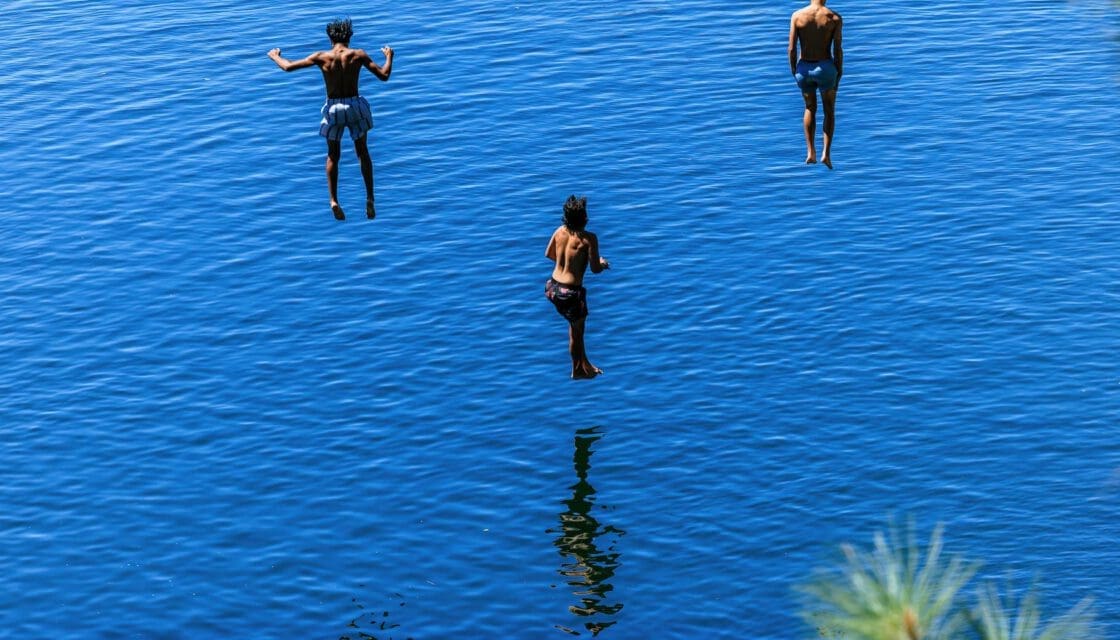 Tyler State Park with kids — three boys leaping into a sunlit lake on a summer day