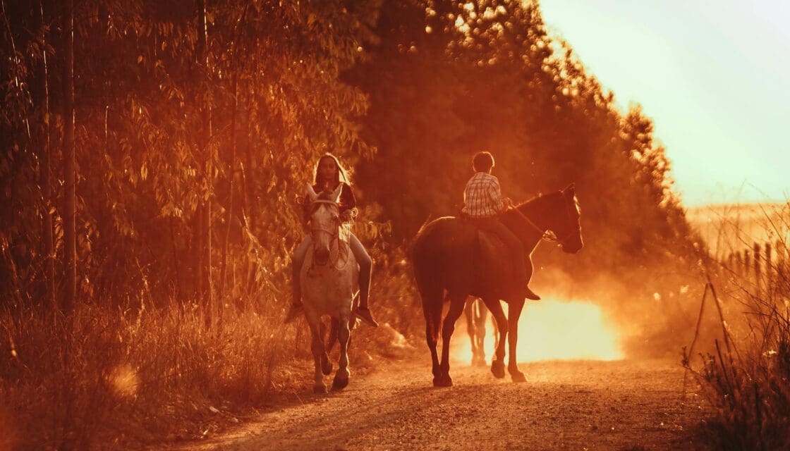 Bandera Texas with kids — young riders on horseback through sunlit Hill Country trails