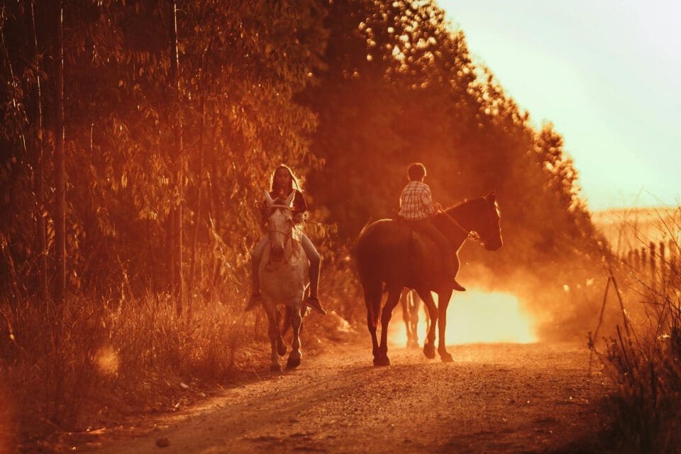 Bandera Texas with kids — young riders on horseback through sunlit Hill Country trails