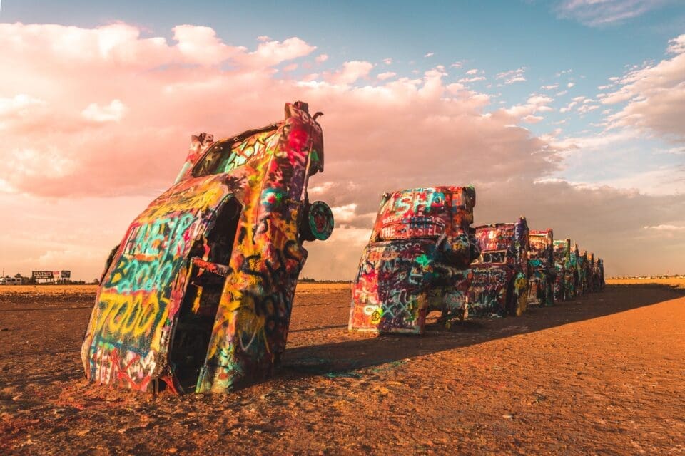 Sunset view at Cadillac Ranch in Amarillo, Texas, featuring the iconic graffiti-covered vintage Cadillac cars buried nose-first in the Texas panhandle landscape