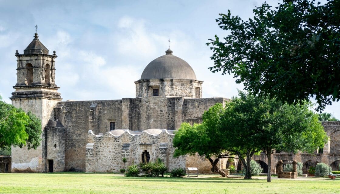 Mission San José historic church in San Antonio, Texas — a landscape view of the ornate stone facade and grounds of the Spanish colonial mission